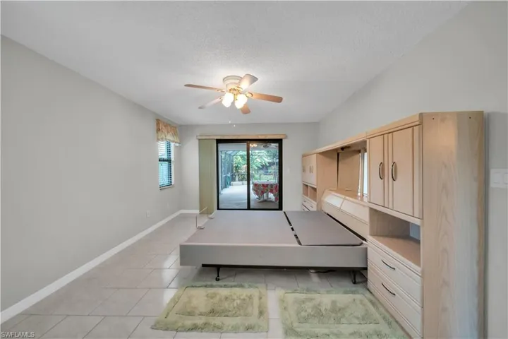 Bedroom featuring access to outside, light tile patterned floors, a textured ceiling, ceiling fan, and built in desk