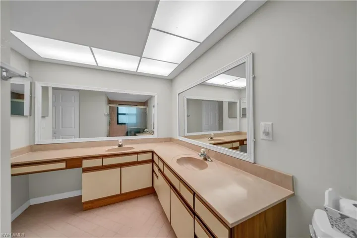 Full bath with double vanity, a shower stall, and light tile patterned flooring