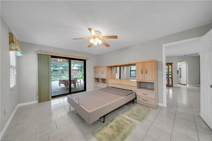 Bedroom with access to outside, arched walkways, light tile patterned floors, a ceiling fan, and a textured ceiling