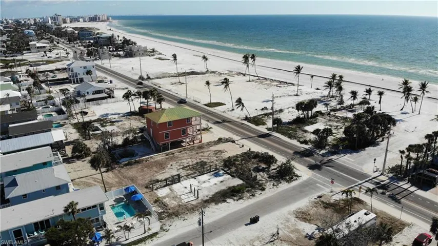 Birds eye view of property with a water view and a beach view