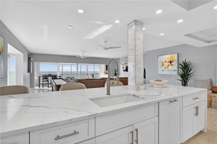 Kitchen featuring white cabinets, light stone counters, open floor plan, and recessed lighting