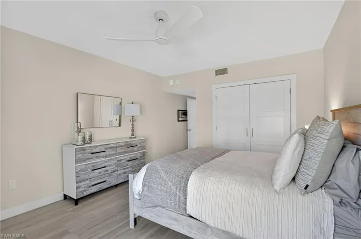 Bedroom with light wood-style flooring, ceiling fan, and a closet