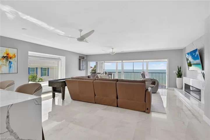 Living room featuring a ceiling fan, light marble finish floors, and a premium fireplace