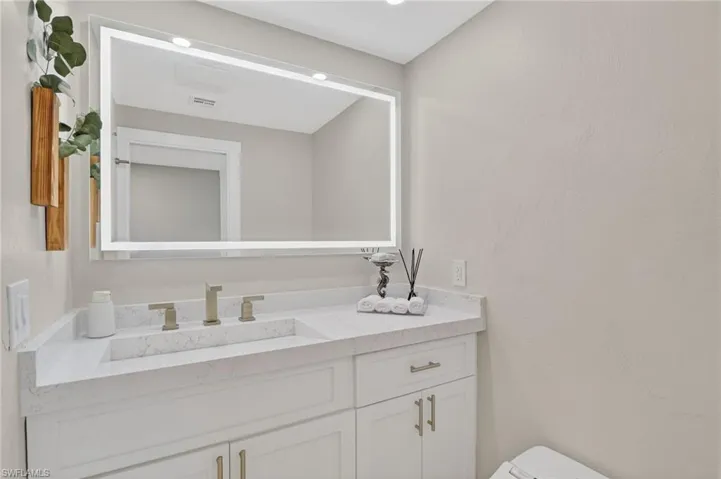 Half bathroom featuring vanity and a textured wall