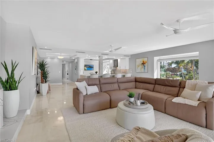 Living room featuring ceiling fan and marble finish floors