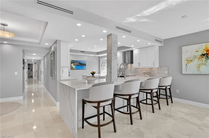 Kitchen featuring white cabinets, light stone countertops, and a peninsula