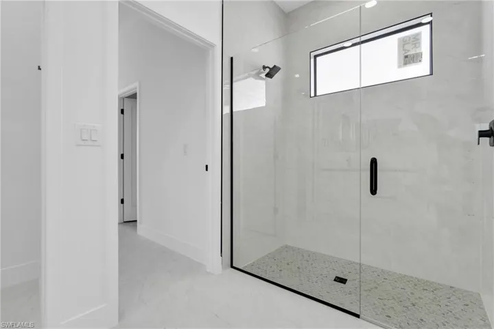Bathroom with a stall shower and light marble finish floors