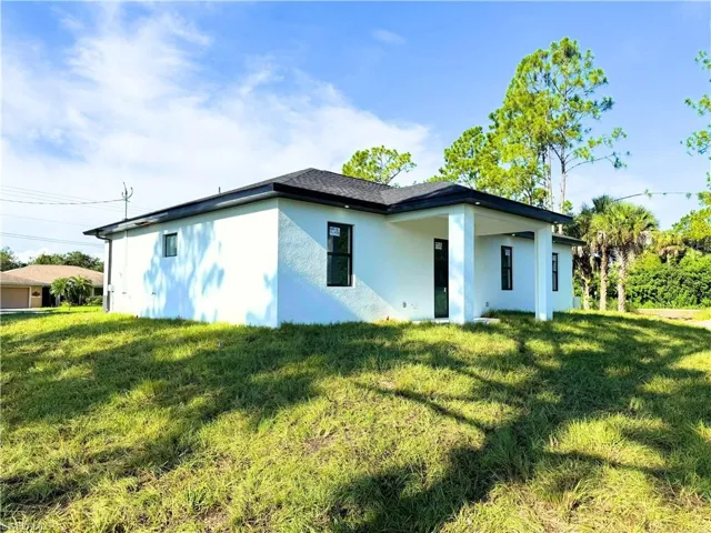 Back of property with a yard and stucco siding