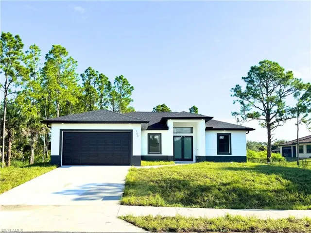 Prairie-style house featuring an attached garage, concrete driveway, a front yard, stucco siding, and roof with shingles