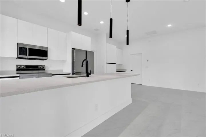 Kitchen featuring white cabinets, modern cabinets, decorative light fixtures, and stainless steel appliances