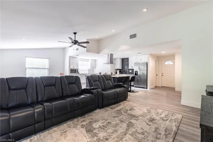 Living room with vaulted ceiling, a ceiling fan, light wood-style floors, and recessed lighting
