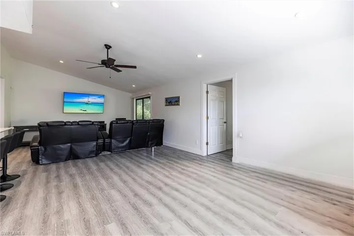 Living room featuring a ceiling fan, recessed lighting, lofted ceiling, and light wood-type flooring