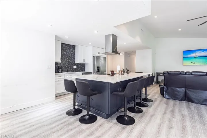 Kitchen with open floor plan, tasteful backsplash, a kitchen breakfast bar, white cabinets, and recessed lighting