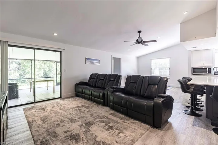 Living area with a ceiling fan, recessed lighting, lofted ceiling, and light wood finished floors