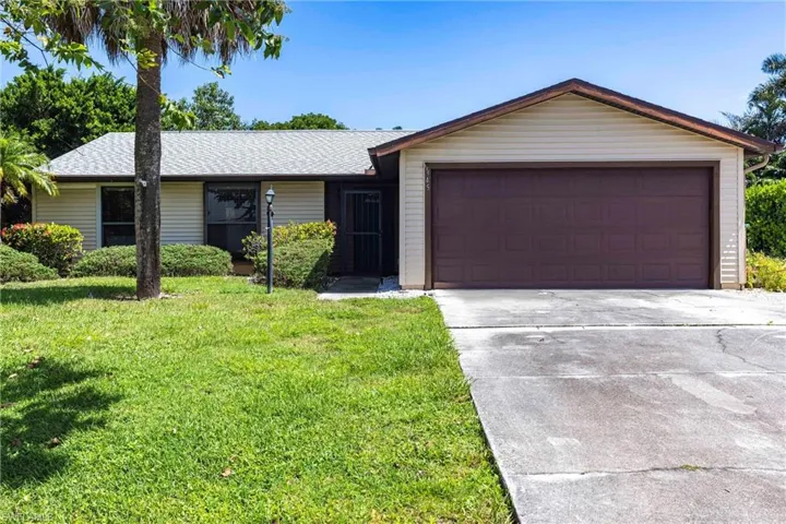 Ranch-style house featuring concrete driveway, a front lawn, roof with shingles, and an attached garage