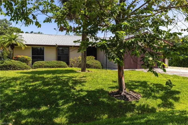 Ranch-style house with a front yard, driveway, a shingled roof, and a garage