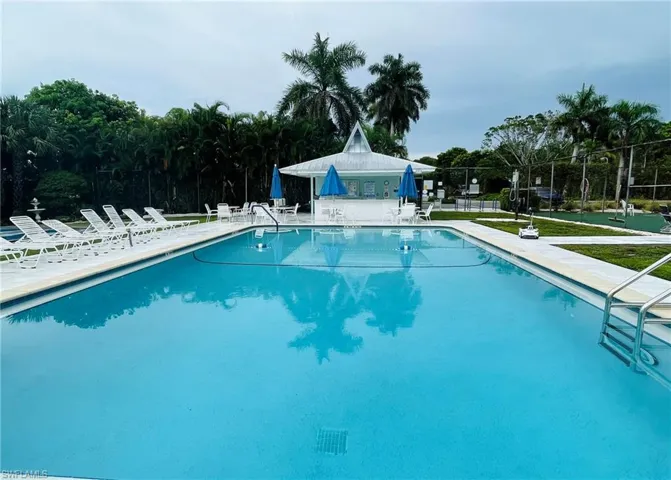 Community pool featuring a patio area and view of wooded area