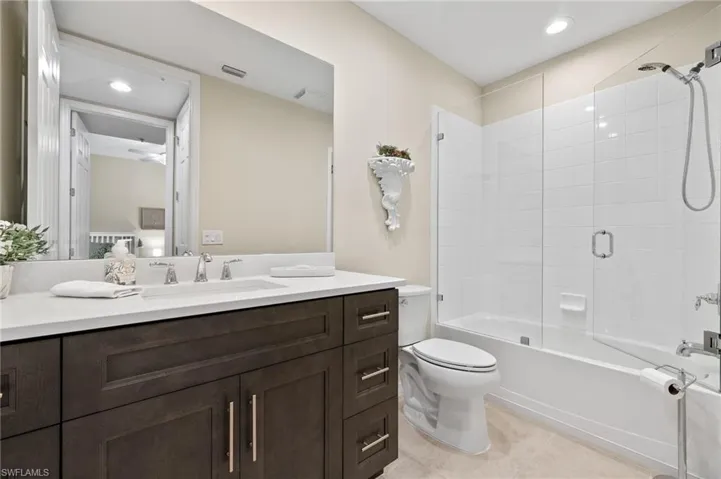 Full bathroom with vanity, tile patterned flooring, tiled shower / bath combo, and toilet