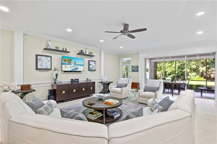 Living room with crown molding, ceiling fan, and light tile patterned floors