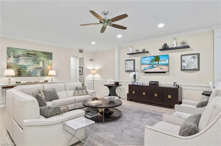 Living room featuring ornamental molding, light tile patterned floors, and ceiling fan
