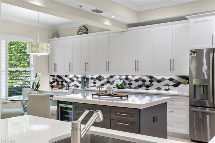 Kitchen featuring white cabinets, a center island, stainless steel fridge, and tasteful backsplash