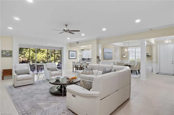 Living room featuring light tile patterned flooring, ceiling fan, ornate columns, and ornamental molding