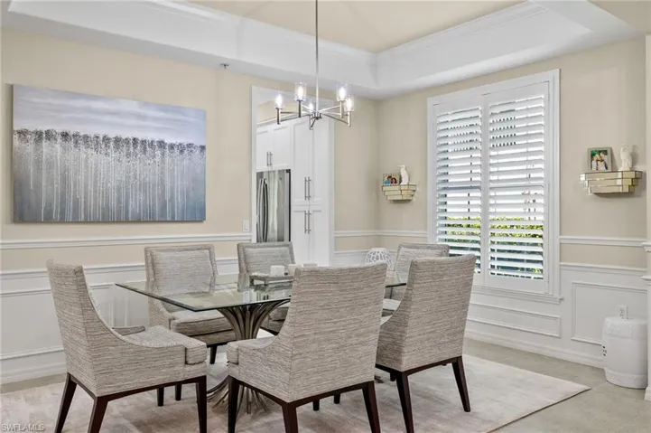 Tiled dining space with a chandelier, crown molding, and a tray ceiling