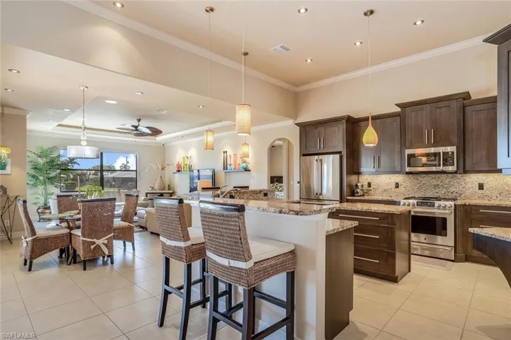 Kitchen featuring a breakfast bar area, a center island, crown molding, hanging light fixtures, and ceiling fan