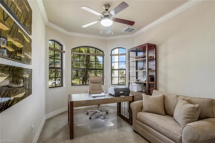 Carpeted office space featuring plenty of natural light, ornamental molding, and ceiling fan