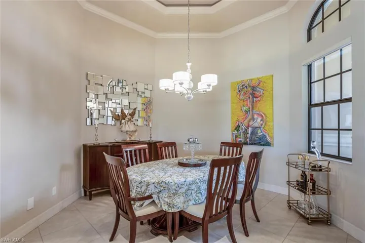 Dining space featuring a high ceiling, ornamental molding, a chandelier, and light tile patterned floors