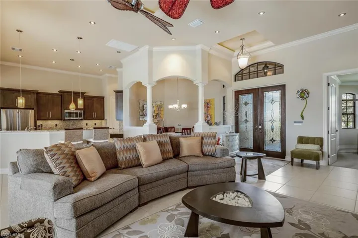 Living room with a towering ceiling, a chandelier, crown molding, french doors, and recessed lighting