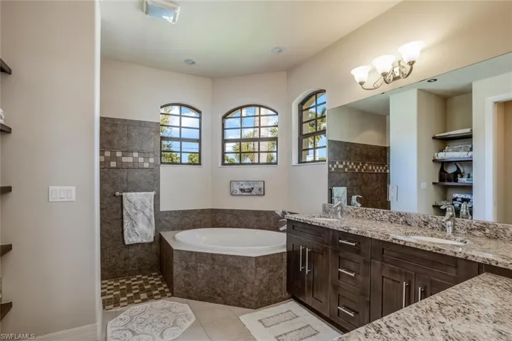 Full bath with a bath, a walk in shower, light tile patterned flooring, double vanity, and a chandelier