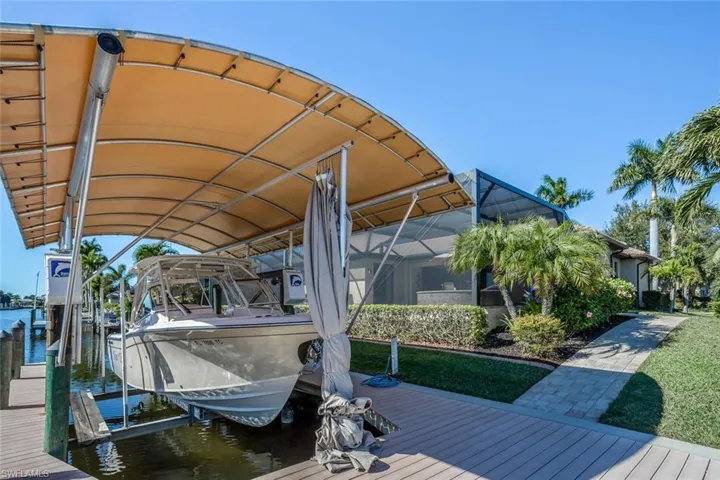 Dock featuring boat lift, glass enclosure, and a water view