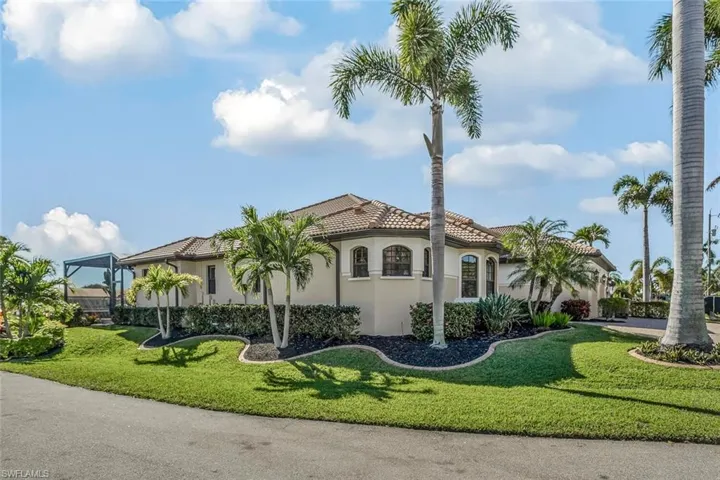 View of front facade with a front yard, stucco siding, and a tile roof