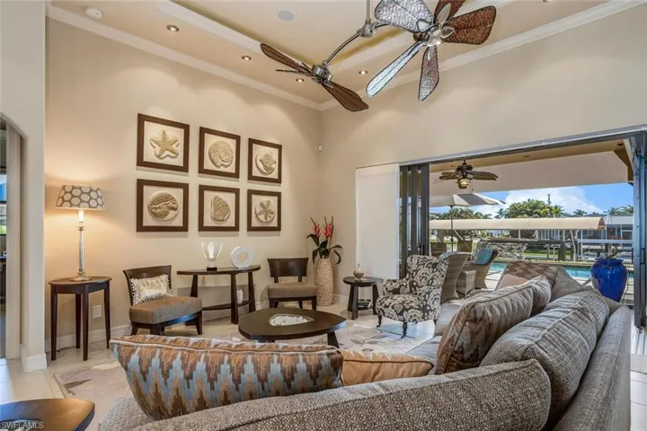 Living room featuring a high ceiling, tile patterned flooring, crown molding, recessed lighting, and a sunroom