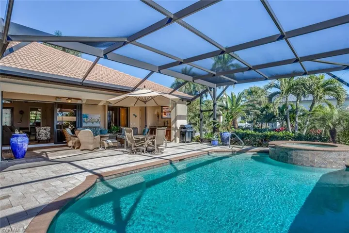 View of pool featuring glass enclosure, a patio, outdoor lounge area, a sunroom, and a pool with connected hot tub