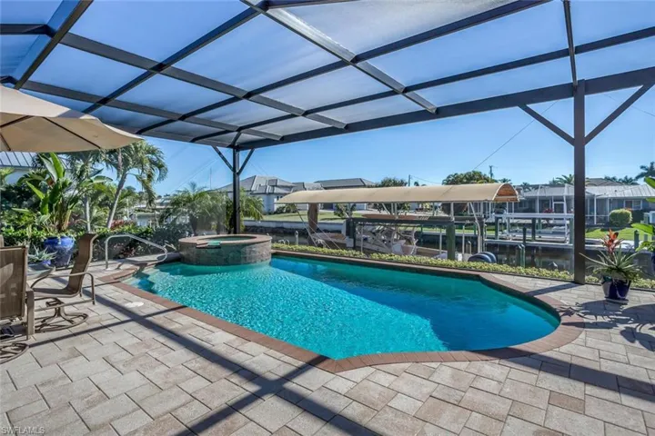 View of swimming pool featuring a patio area, a pool with connected hot tub, and a lanai