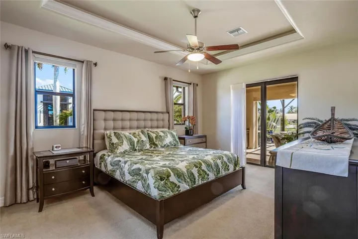 Bedroom featuring a tray ceiling, access to exterior, carpet flooring, and ceiling fan