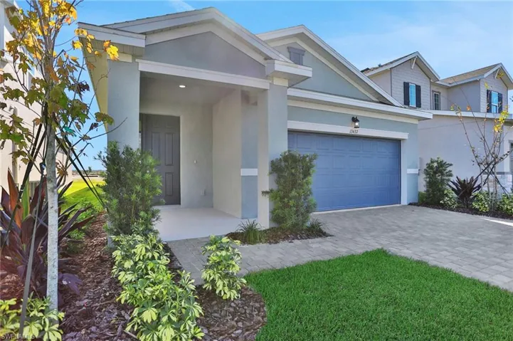 View of front of home with stucco siding, decorative driveway, a garage, and a front lawn
