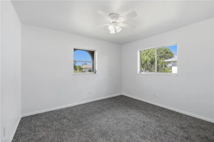 Spare room with dark colored carpet and a ceiling fan