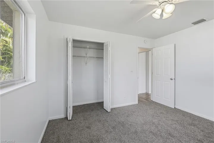 Unfurnished bedroom with multiple windows, carpet floors, ceiling fan, and a closet