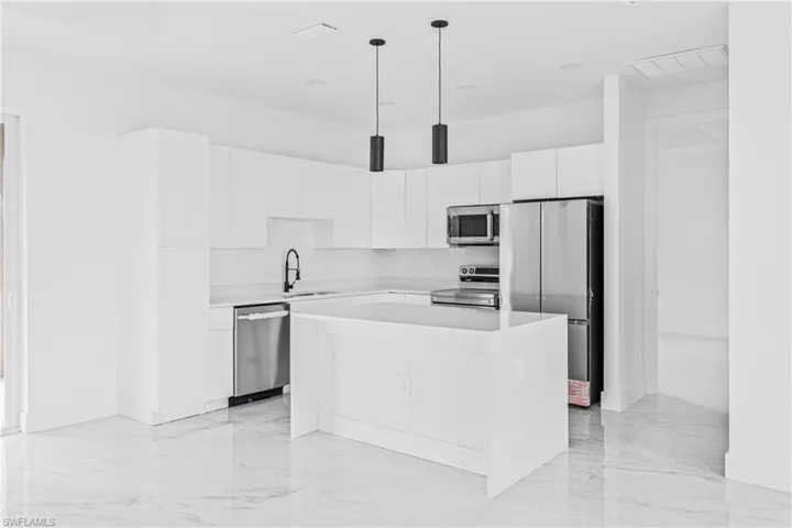 Kitchen featuring flat-panel white cabinetry, stone-surface countertops, a central island, stainless steel appliances, and polished stone-finish flooring