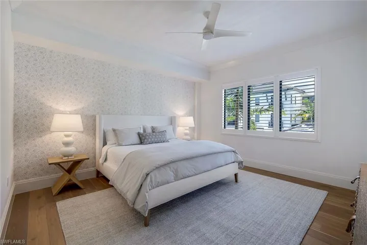 Spacious primary bedroom featuring Legno Bastone wood floors, Serena and Lily wallpaper, western exposure and access to the large balcony