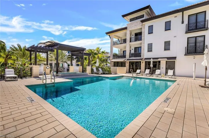 View of pool with a pergola and spa
