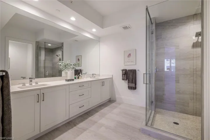 Large primary bathroom featuring double sinks, large glass shower, stone flooring