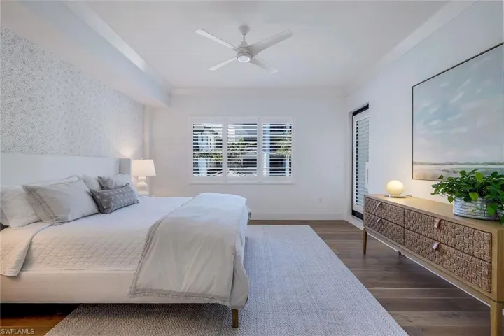 Spacious primary bedroom with Legno Bastone wood floors, Serena & Lily wallpaper and access to the large balcony