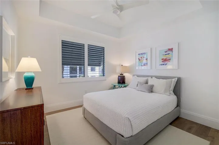 Guest bedroom with wood floors, western exposure and a raised ceiling