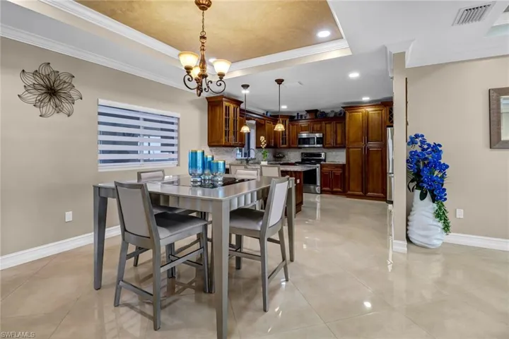 Tiled dining room with a chandelier, crown molding, and a raised ceiling