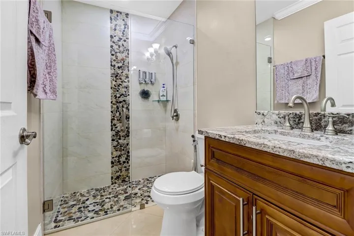 Bathroom featuring toilet, tile floors, a shower with shower door, ornamental molding, and large vanity