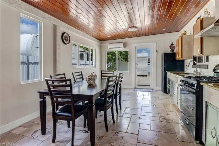 enclosed Lanai with an outdoor kitchen for gathering with a split AC system, travertine tile and a beautiful tongue and groove wood ceiling.